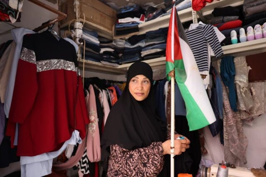 A shop owner carries a Palestinian flag in her store in the Shatila refugee camp in Beirut