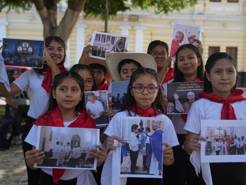 Members of a religious children's choir display photos of newly elected Pope Leo XIV