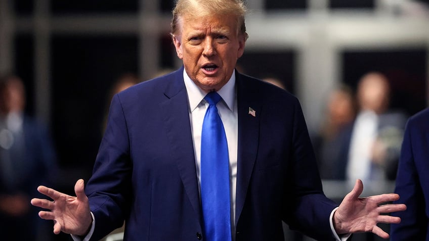 Donald Trump addressing media in blue tie, blue coat outside courthouse