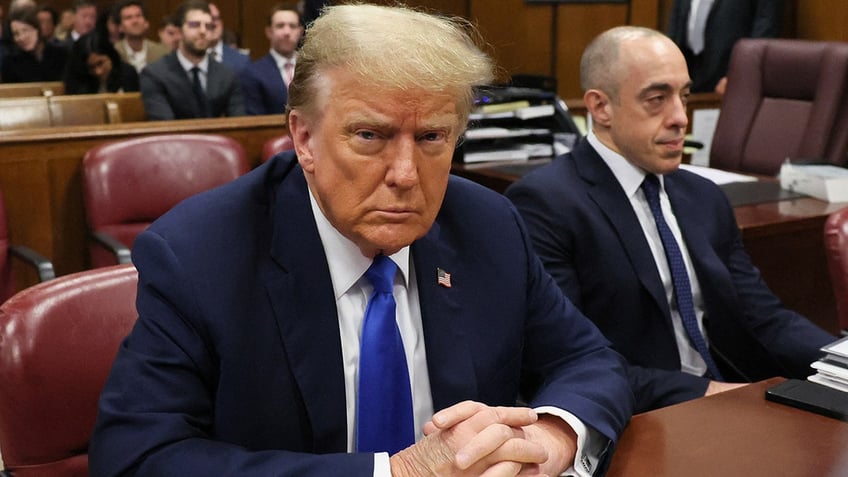 Donald Trump in blue tie with lawyer at defense table in court