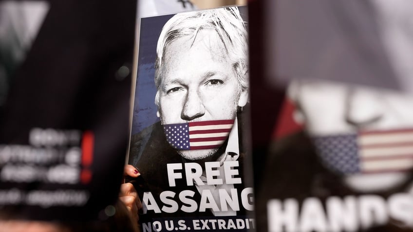 Protesters hold placards outside the High Court in London ahead of Julian Assange's hearing
