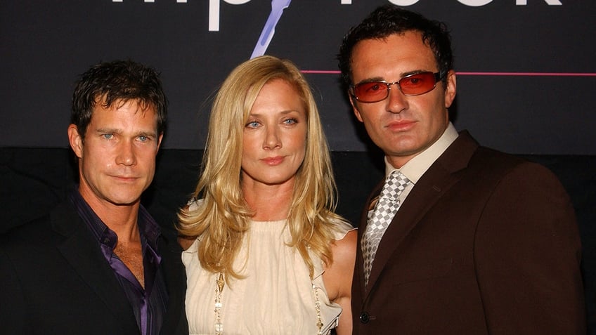 The cast of "Nip/Tuck" leaning against each other closely looking serious.