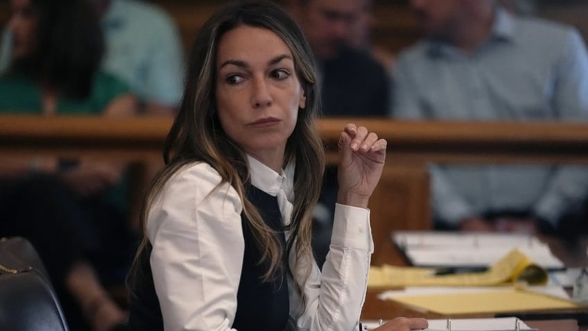 Karen Read waits as her legal team meets at the side bar during Reid's trial in Norfolk Superior Court, Friday, June 14, 2024, in Dedham, Mass.