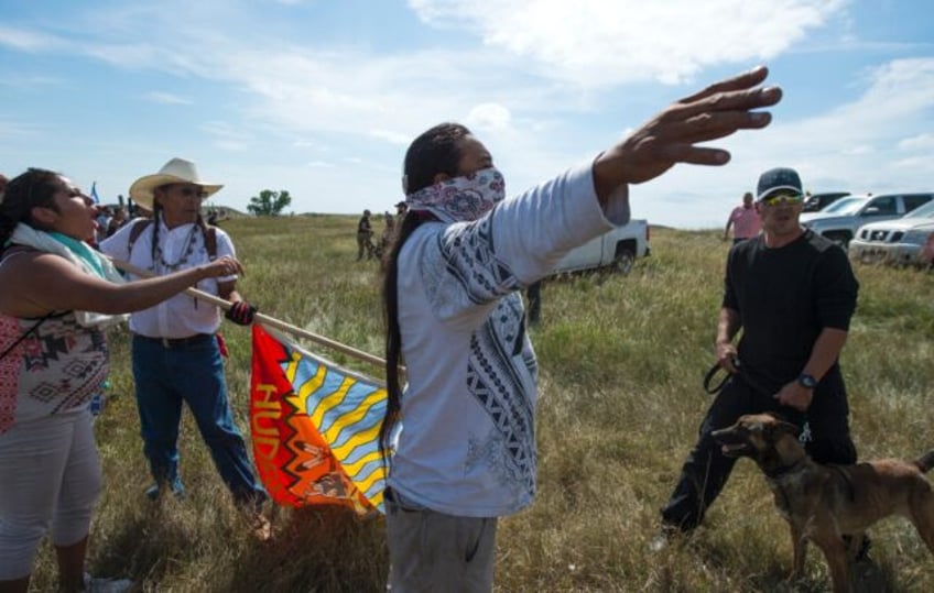 A Native American protestor holds up his arms as he and other protestors are threatened by