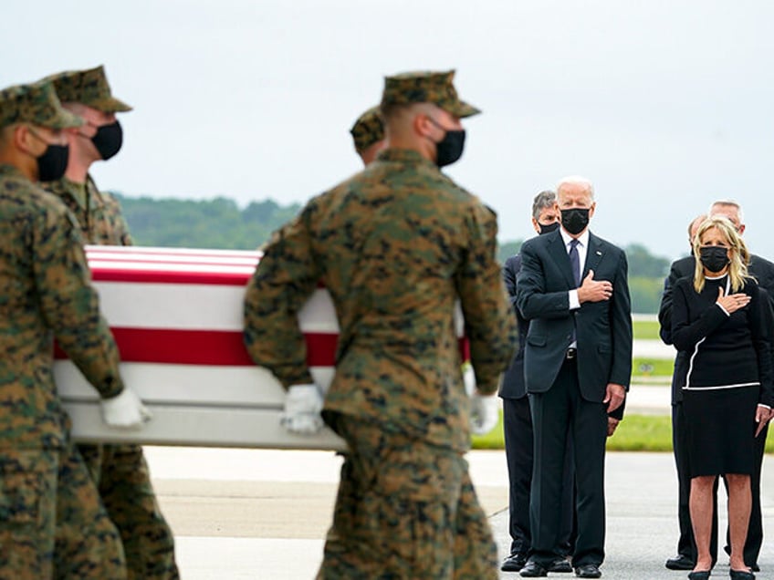 President Joe Biden and first lady Jill Biden watch as a Marine Corps carry team moves a t