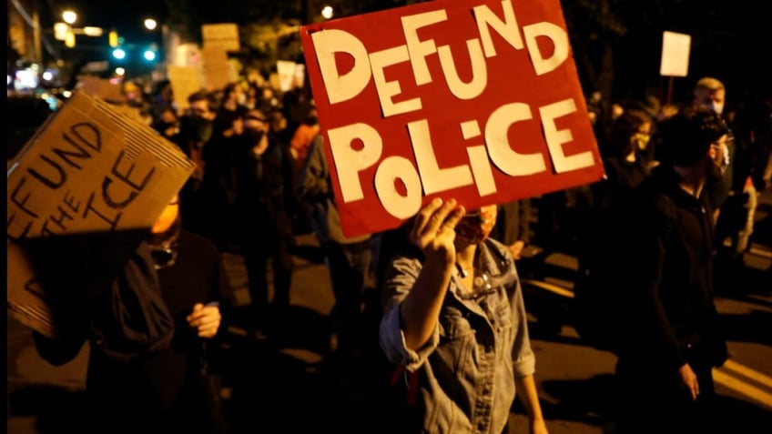 protester with a 'defund police' sign