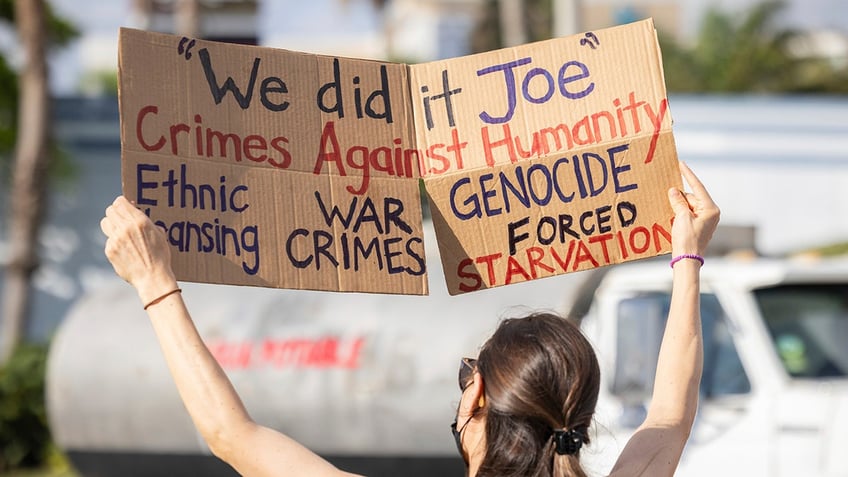 San Juan protester holds sign condemning Biden and Harris for "war crimes."