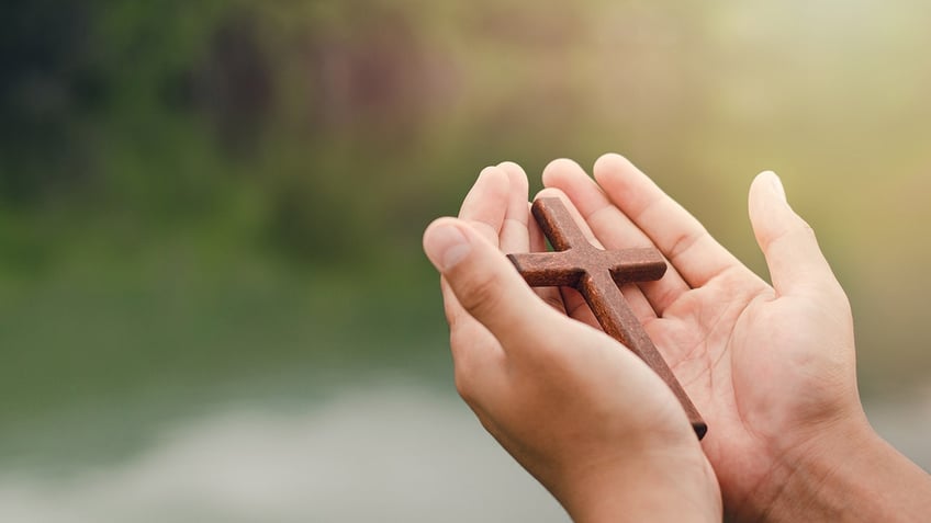 Hands holding wooden cross