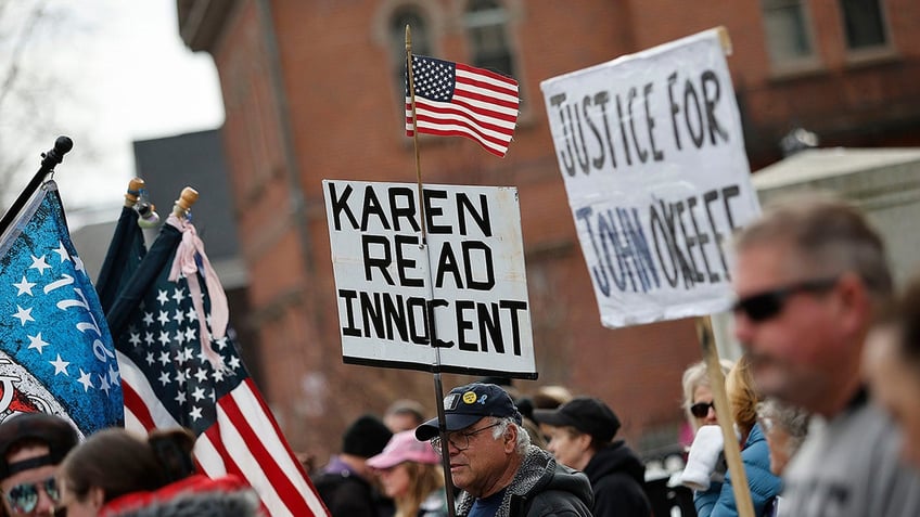 Karen Read supporters and protestors holding signs and American flags outside the court room.