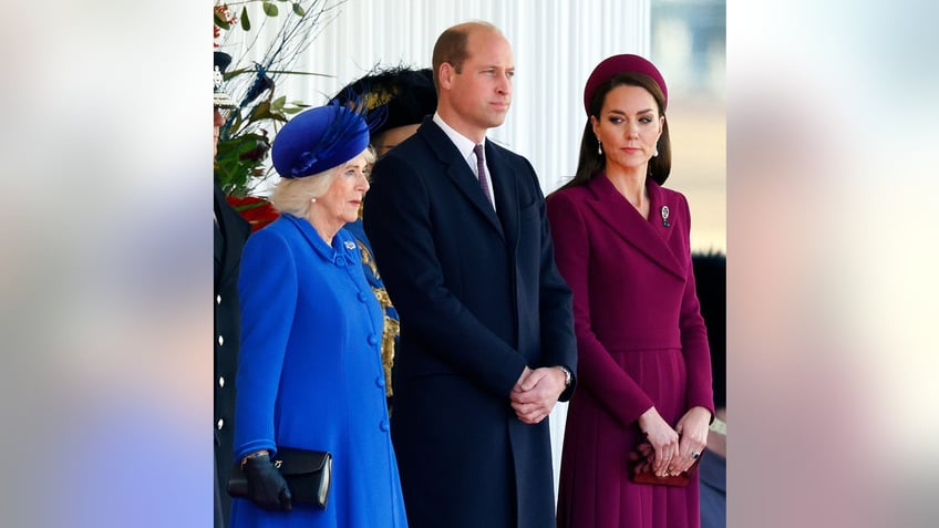 Kate Middleton looking at Queen Camilla as the Princess of Wales stands next to Prince William