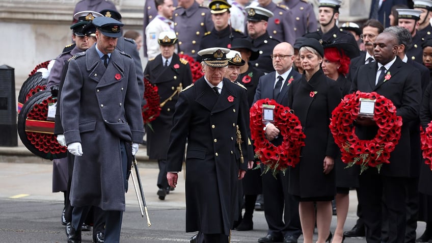 Prince William and Prince Charles walking with a group to lay wreaths