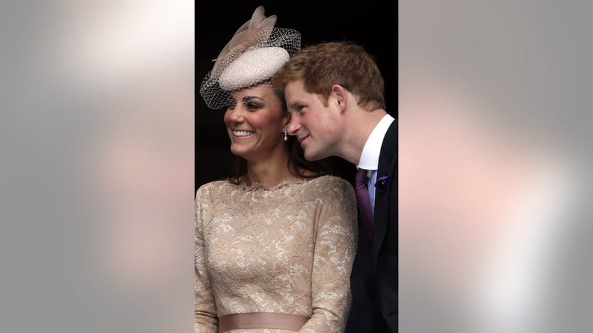 Prince Harry leaning next to Kate Middleton who is smiling