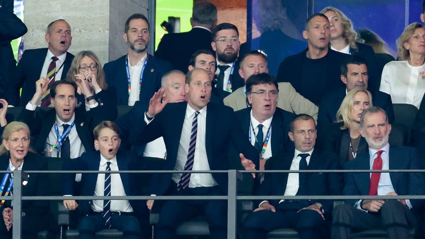 Prince George and Prince William appear stunned in suits as they cheer on from the stadium