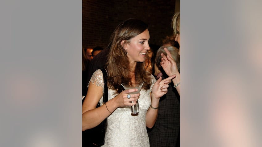 Kate Middleton holding onto a cocktail and pointing at someone