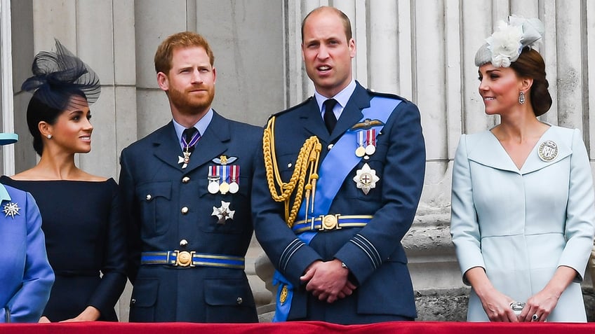 The royal family looking serious standing on the palace balcony.