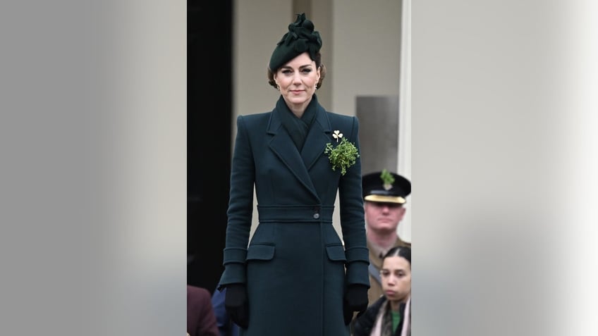 Kate Middleton standing in a fitted green coat with matching hat and shamrocks pinned to her.