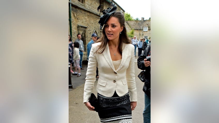 A young Kate Middleton walking outdoors with photographers following her.