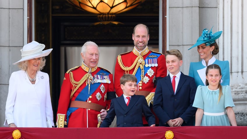 The Royal family in royal regalia standing on the balcony of Buckingham Palace.