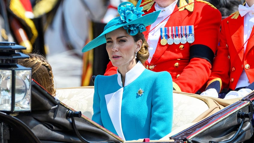 Kate Middleton in a bright blue coat dress sitting in a carriage.