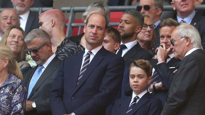 Prince William standing next to Prince George at a stadium