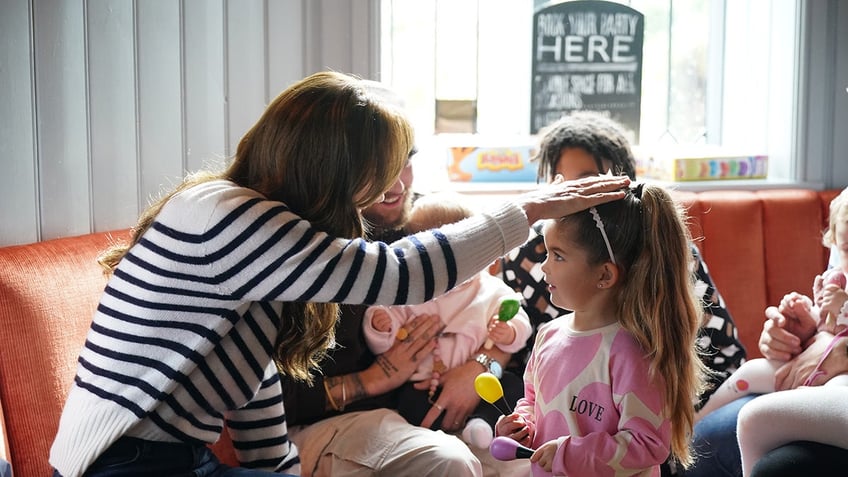 Kate Middleton patting a little girls head.