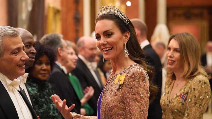 Kate Middleton smiling wearing a tiara and sparkling dress with a sash.