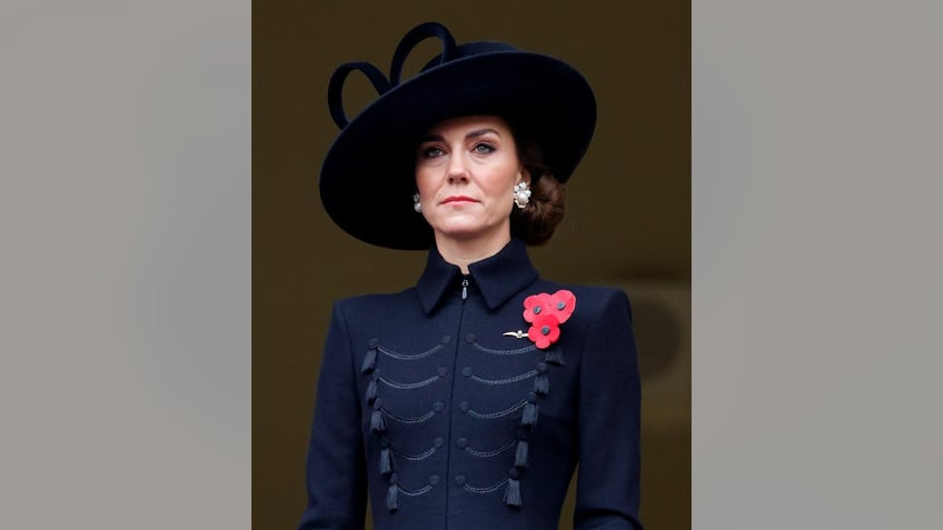 Kate Middleton looking somber in a black suit with a poppy flower pin.