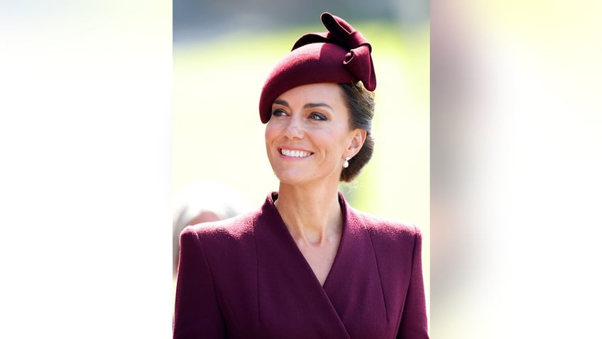 Kate Middleton wearing a purple suit and a matching hat.