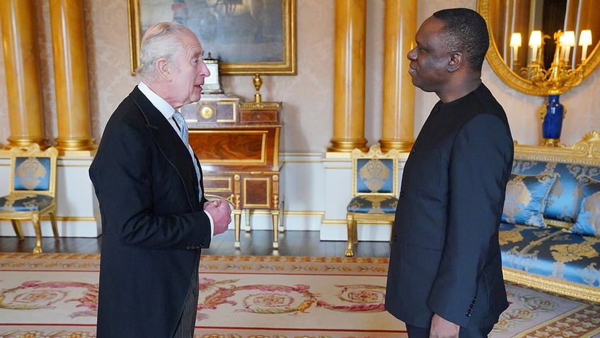 King Charles greeting a man inside Buckingham Palace