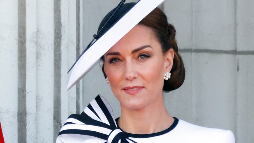 Kate Middleton wearing a white and navy matching dress and hat on a slant