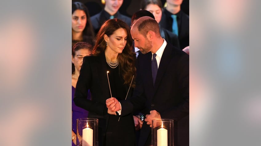 Kate Middleton holding a candle leaning into Prince William as they both wear black and look somber.