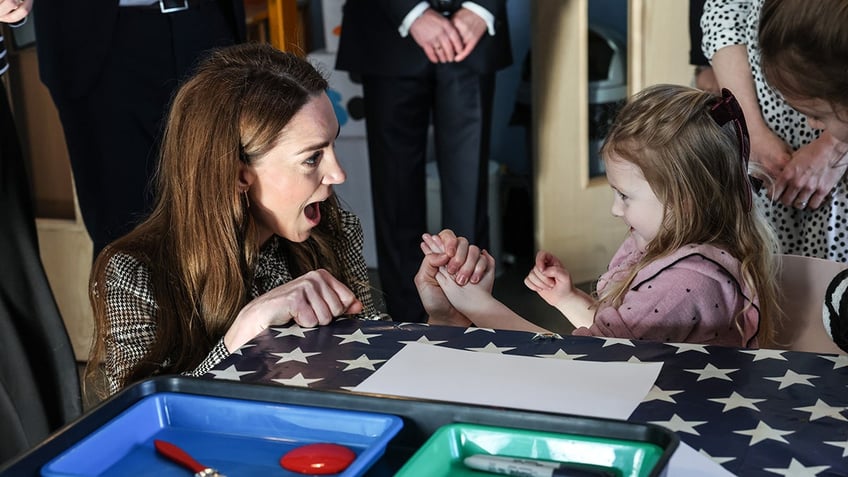 Kate Middleton playful gasping in surprise while holding a smiling little girl's hand