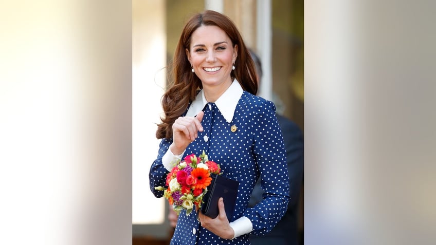 Kate Middleton wearing a polka dot dress and holding a bouquet of flowers