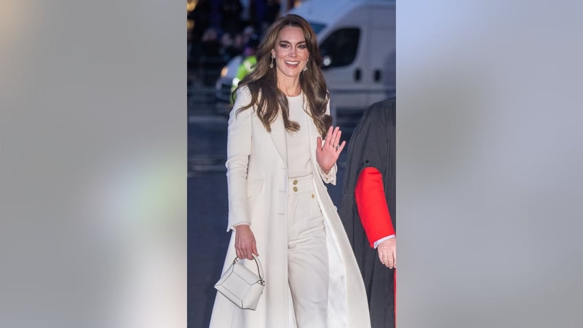 Kate Middleton wearing a white outfit and a matching coat waving