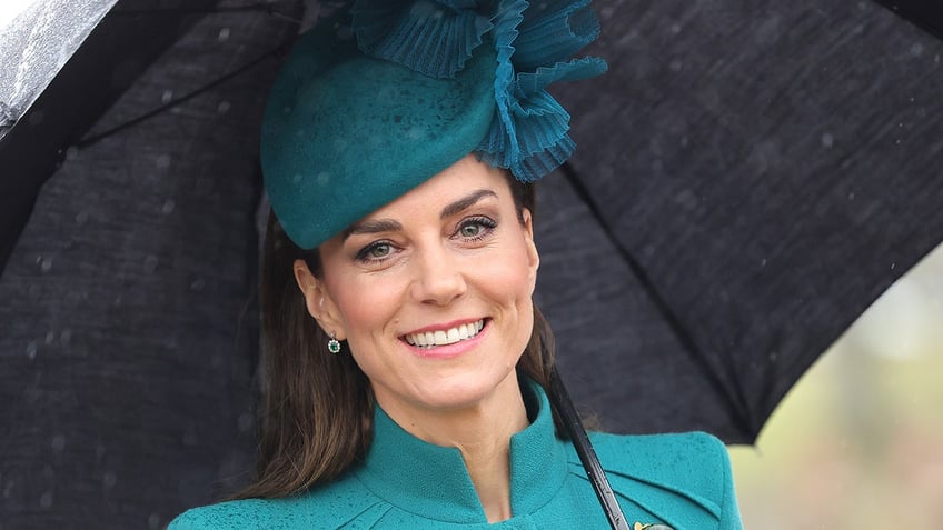 Kate Middleton holding an umbrella while wearing a fascinator