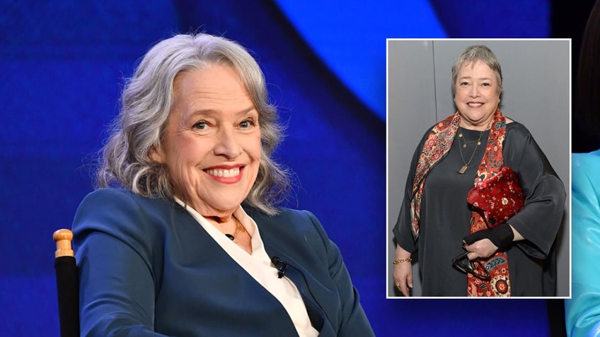 Kathy Bates smiles in a blue suit, walks red carpet.