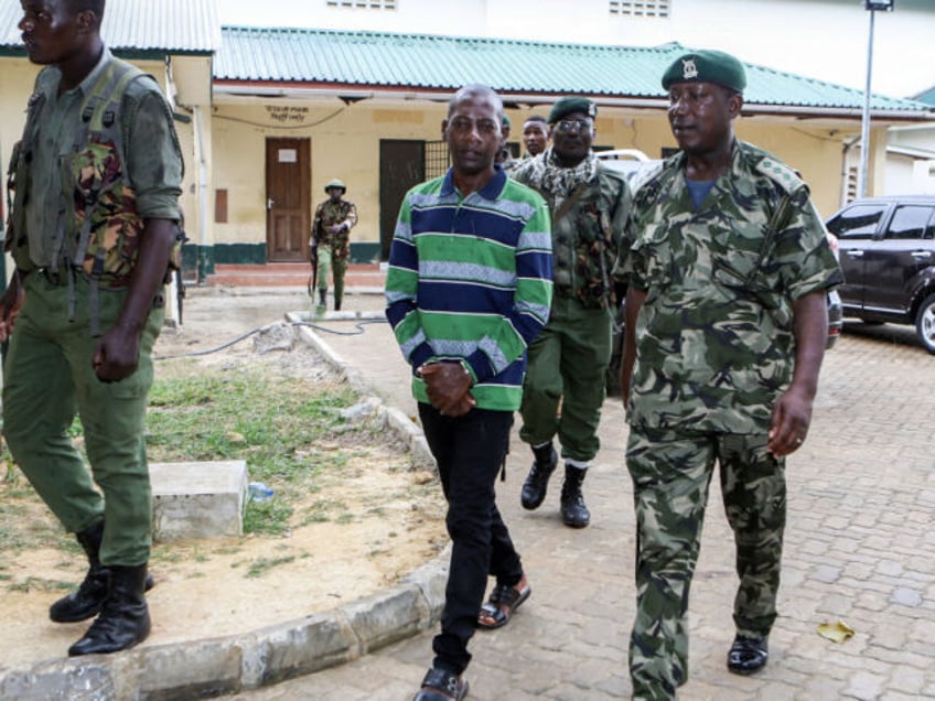 Self-proclaimed pastor Paul Nthenge Mackenzie (C) walks surrounded by Kenya Police Officers as he appears at the Shanzu Law Courts in Mombasa on January 18, 2024. A Kenyan court on January 18, 2024 charged the leader of a starvation cult with terrorism over the deaths of more than 400 of …