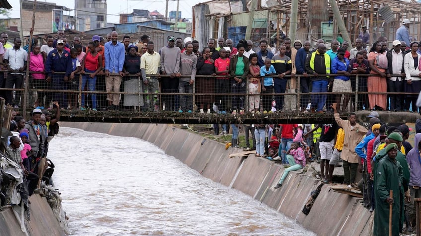 People stand on a bridge, as they watch houses in riparian land being demolished in the Mukuru area of Nairobi, Kenya