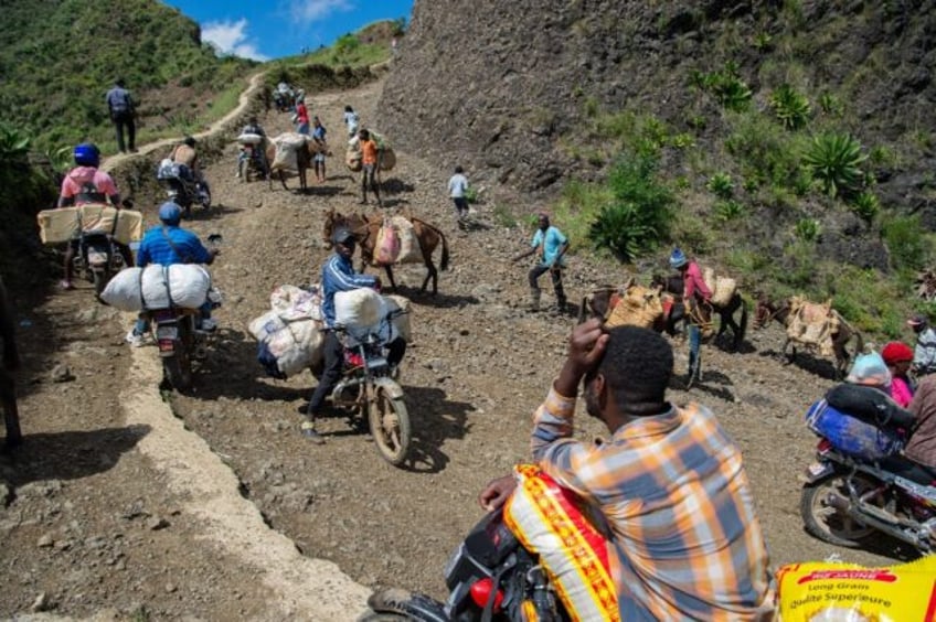 Vendors hauling their goods travel on a rocky, cliff-lined road to avoid gangs in the Port