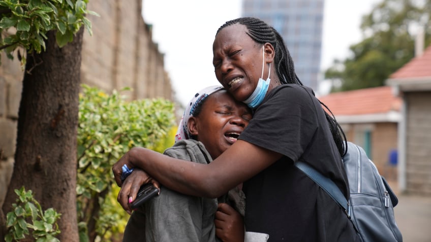 Edith Wanjiku, left, weeps after viewing the body of her son