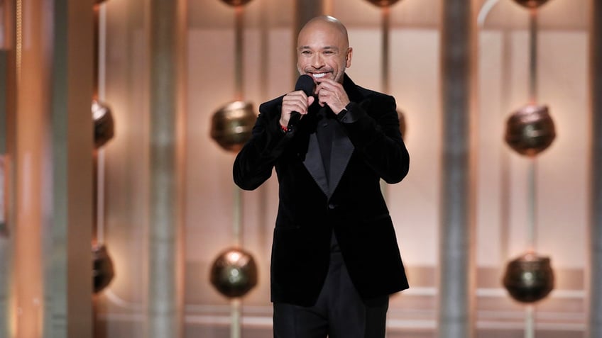 Jo Koy holds the microphone on stage at the Golden Globes