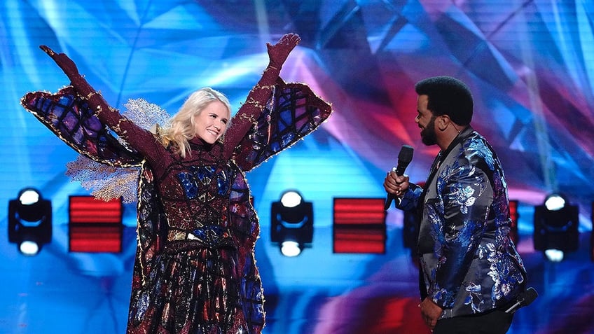 Elizabeth Smart with her arms raised in costume