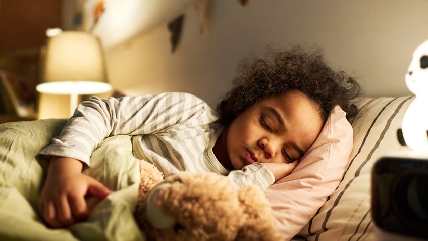 child sleeping in bed with toy