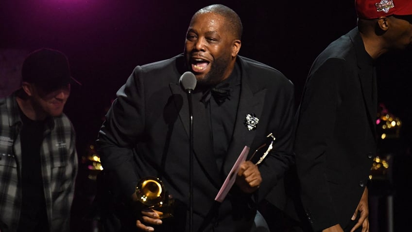 Rapper Killer Mike in a black suit talks on stage after winning a Grammy