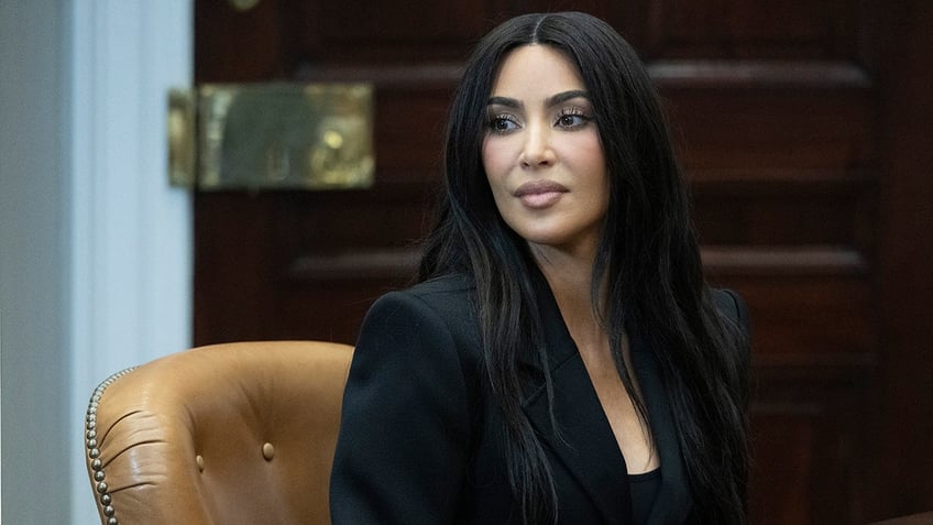 Kim Kardashian looks concentrated behind the table as she sits with reason pardon recipients and VP Kamala Harris (not pictured)