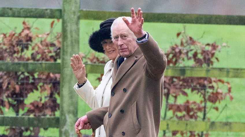 King Charles III waves to onlookers walking with Queen Camilla