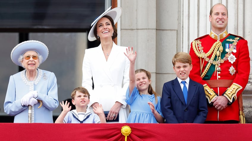 Prince and Princess of Wales on the palace balcony with their children standing next to a smiling queen elizabeth