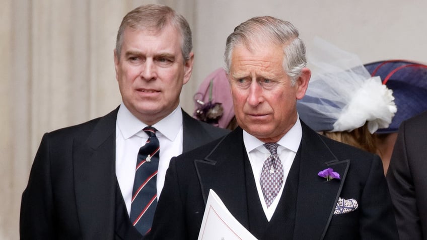 A close-up of Prince Andrew walking behind King Charles in matching black suits.