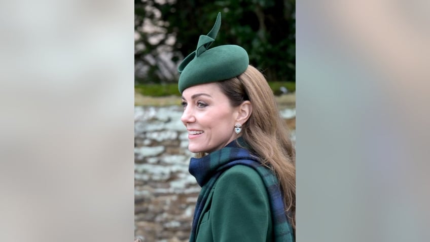 A close-up of Kate Middleton wearing a green coat, a plaid scarf and a matching fascinator.