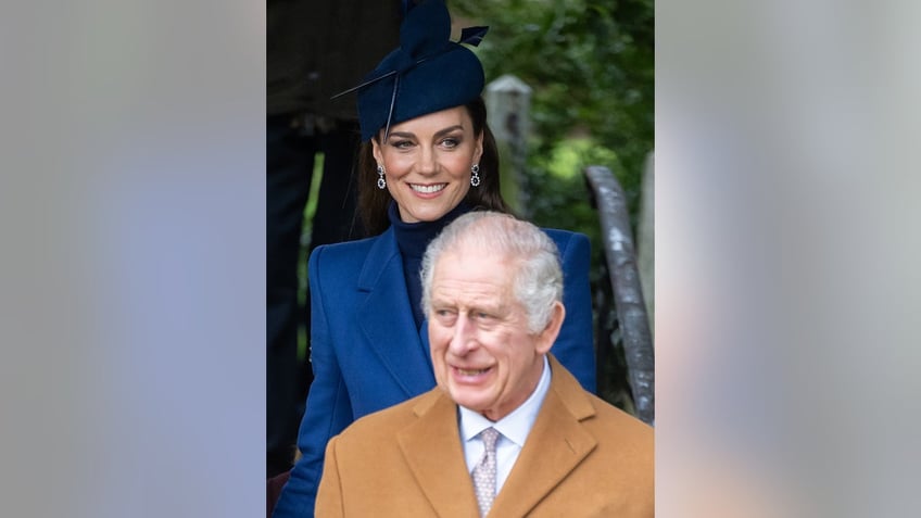 Kate Middleton in a blue coat dress walking behind King Charles in a beige coat